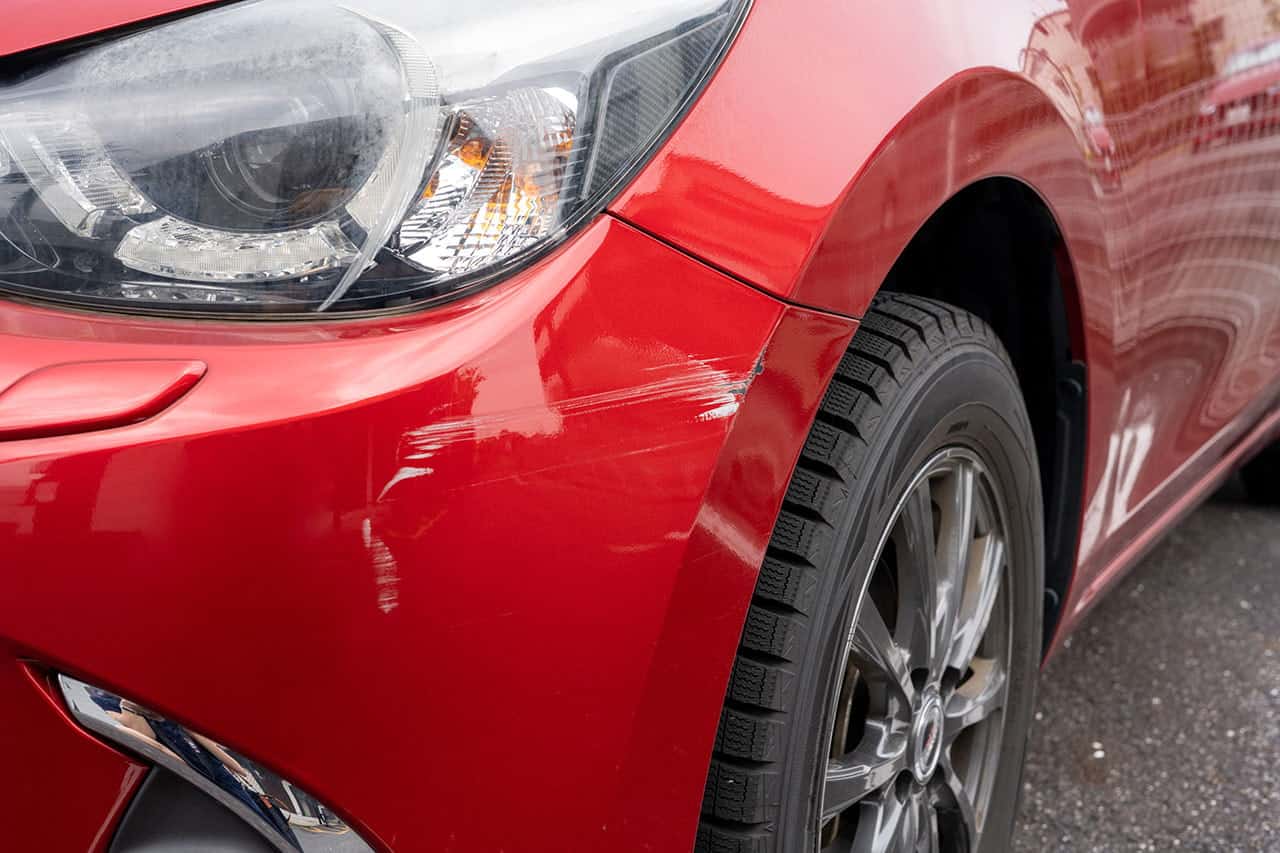 車のフロントに傷がある赤い車